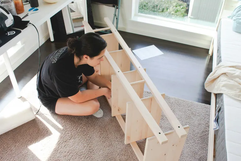 A woman assembling a wooden rack.